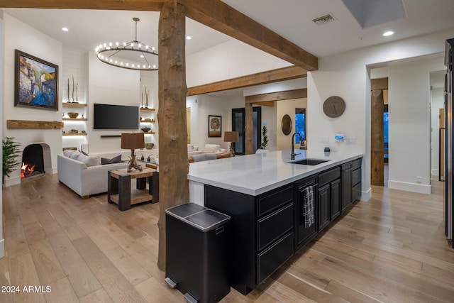 kitchen featuring pendant lighting, sink, light hardwood / wood-style floors, and a notable chandelier