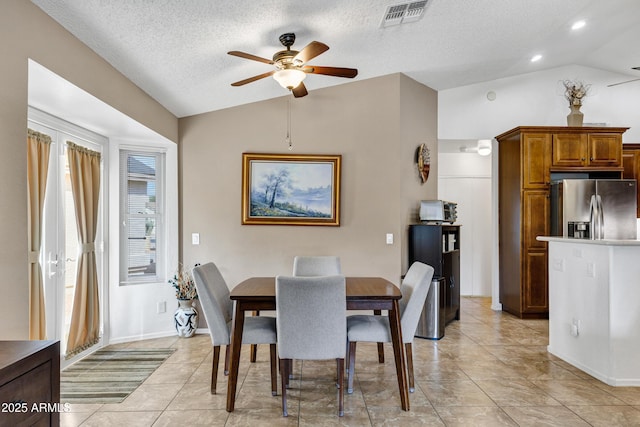 tiled dining room with lofted ceiling, ceiling fan, and a textured ceiling