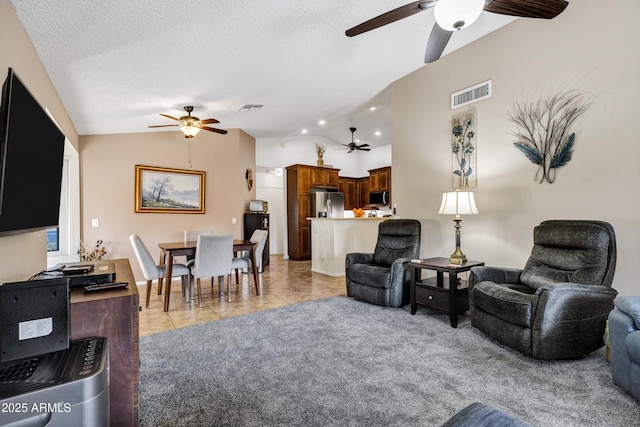 living room with ceiling fan, lofted ceiling, a textured ceiling, and light tile patterned floors