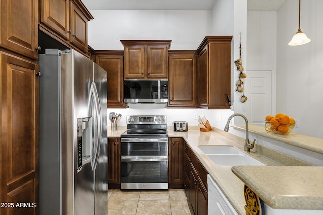 kitchen with pendant lighting, appliances with stainless steel finishes, sink, and light tile patterned floors