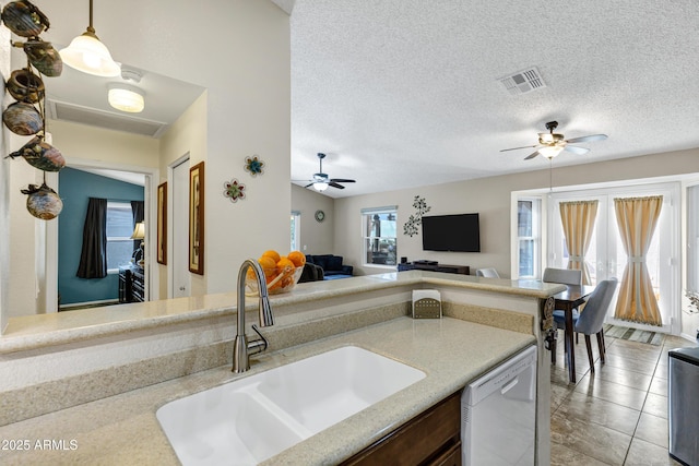 kitchen with hanging light fixtures, dishwasher, sink, and a textured ceiling