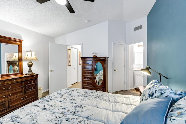 carpeted bedroom featuring ensuite bath, a textured ceiling, and ceiling fan