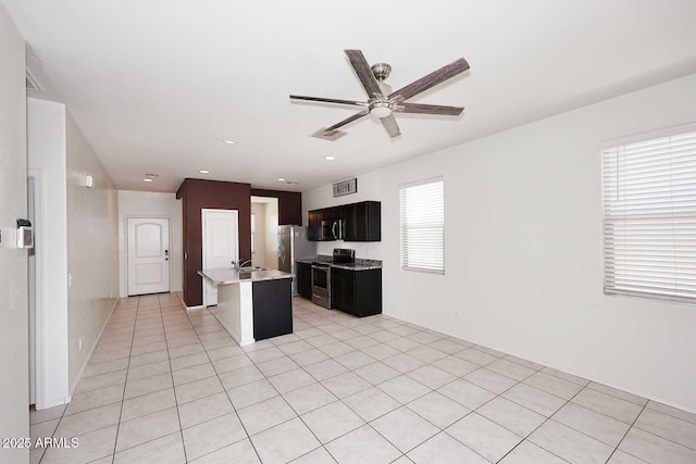 29932 N Paloverde Dr, Florence, AZ 85132 - kitchen with appliances with stainless steel finishes, a sink, ceiling fan, an island with sink, and light tile patterned floors