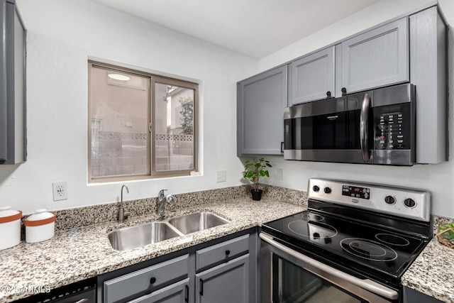 kitchen featuring appliances with stainless steel finishes, sink, and gray cabinetry