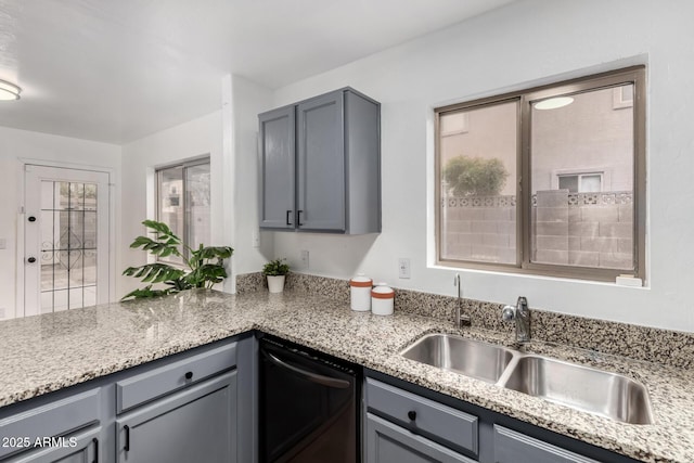 kitchen featuring gray cabinets, black dishwasher, sink, and light stone counters