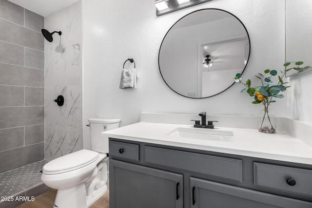 bathroom featuring tiled shower, vanity, and toilet