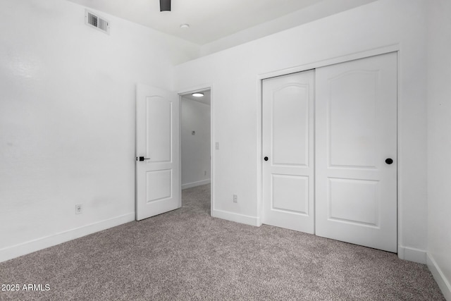 unfurnished bedroom with light colored carpet and a closet