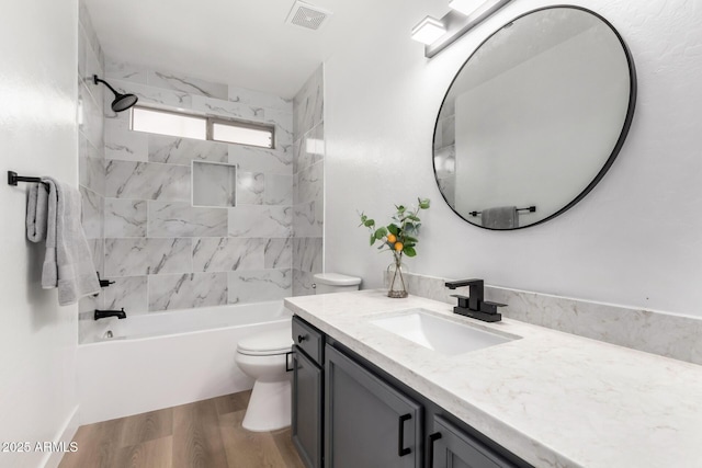 full bathroom with wood-type flooring, toilet, tiled shower / bath combo, and vanity