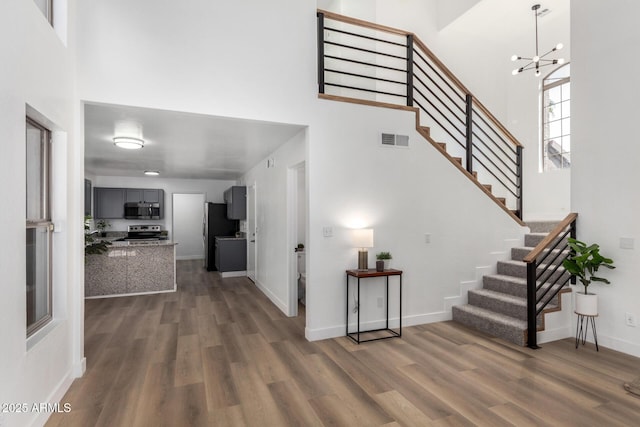 interior space with dark hardwood / wood-style flooring, a towering ceiling, and an inviting chandelier