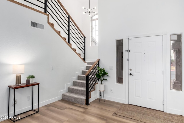 foyer with a towering ceiling, light hardwood / wood-style floors, and a chandelier