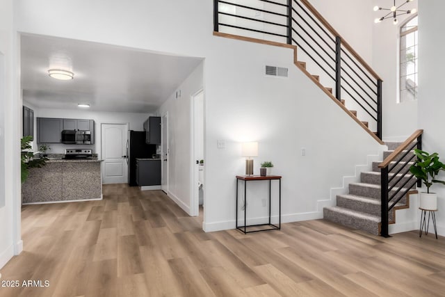 interior space with a towering ceiling, light hardwood / wood-style floors, and a chandelier