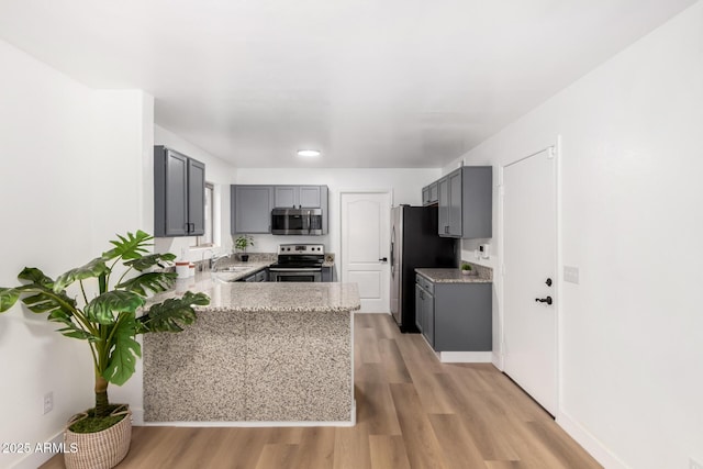 kitchen featuring sink, gray cabinets, appliances with stainless steel finishes, kitchen peninsula, and light wood-type flooring