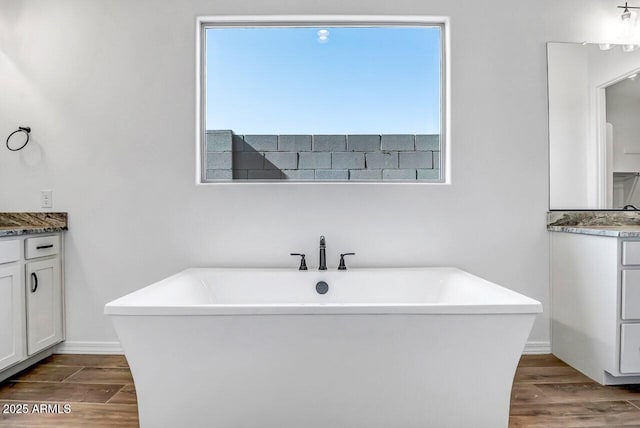 bathroom with hardwood / wood-style flooring, vanity, and a tub to relax in