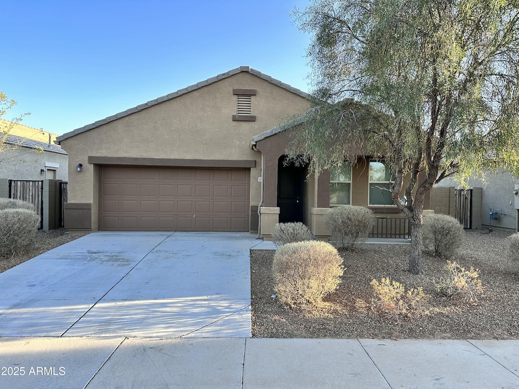 view of front of property with stucco siding, an attached garage, concrete driveway, and fence