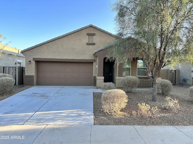 view of front of property with stucco siding, an attached garage, concrete driveway, and fence