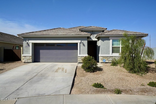 prairie-style house with stucco siding, concrete driveway, a garage, stone siding, and a tiled roof