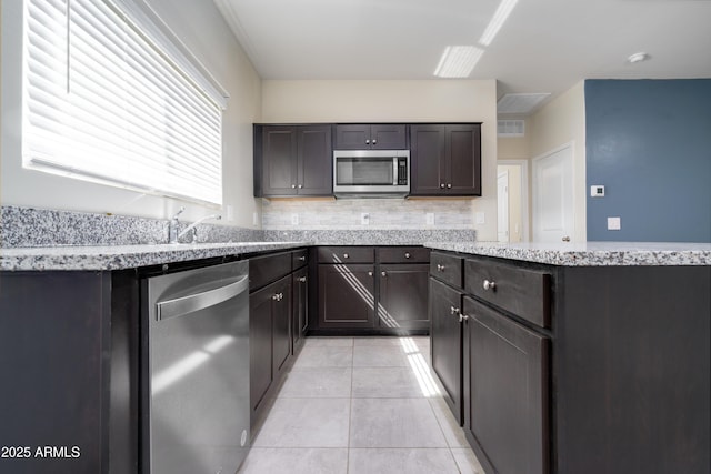 kitchen with dark brown cabinetry, light tile patterned floors, visible vents, decorative backsplash, and stainless steel appliances