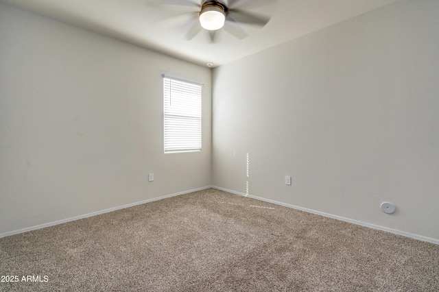 carpeted spare room with a ceiling fan and baseboards