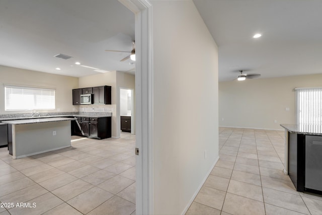 kitchen featuring light tile patterned floors, ceiling fan, stainless steel microwave, and dishwasher