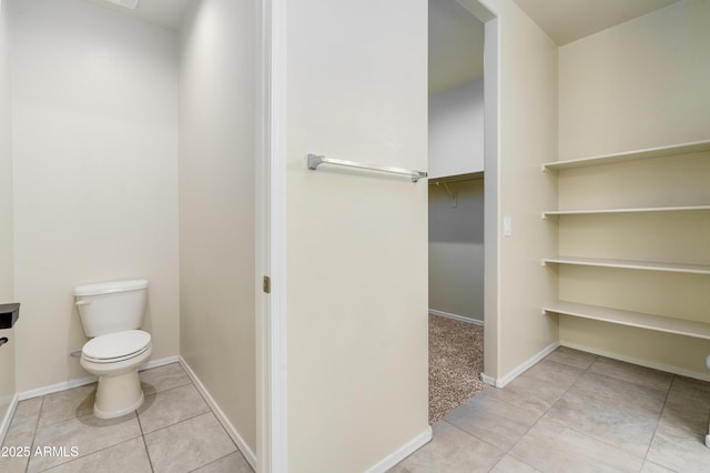 bathroom with toilet, baseboards, and tile patterned floors