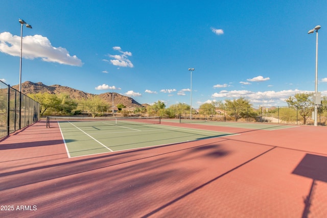 view of tennis court featuring community basketball court, a mountain view, and fence