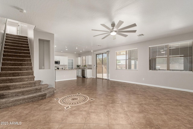 unfurnished living room featuring stairs, a ceiling fan, visible vents, and baseboards