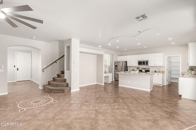 kitchen featuring visible vents, white cabinets, ceiling fan, a kitchen island, and stainless steel appliances