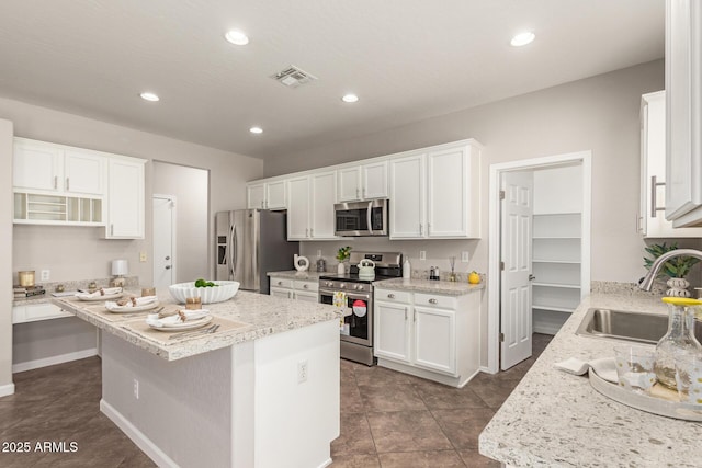 kitchen with stainless steel appliances, a sink, a center island, and white cabinets