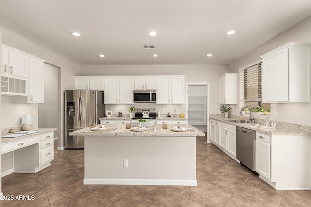 kitchen with visible vents, white cabinets, a center island, stainless steel appliances, and a sink