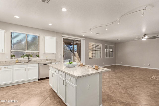 kitchen featuring white cabinets, open floor plan, a center island, light stone countertops, and stainless steel dishwasher