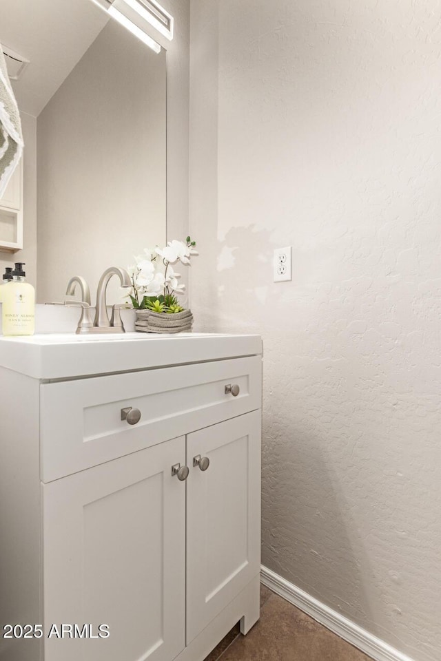 bathroom featuring a textured wall, vanity, and baseboards