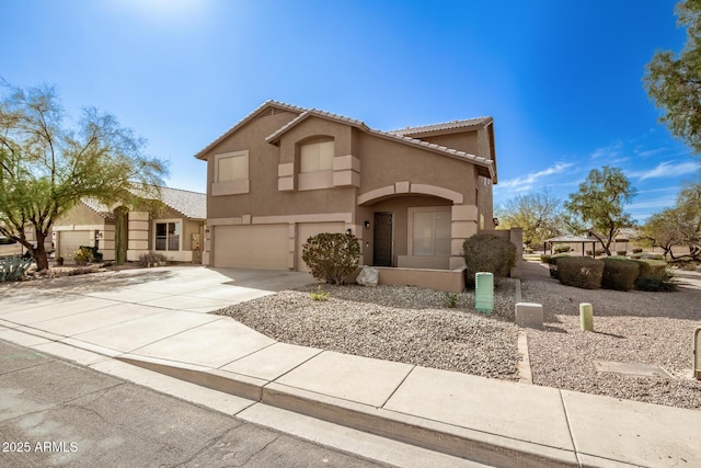 mediterranean / spanish home with an attached garage, driveway, a tiled roof, and stucco siding