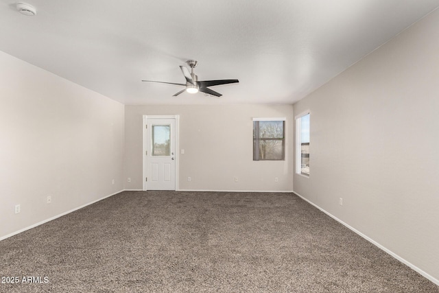 carpeted empty room featuring a ceiling fan and baseboards