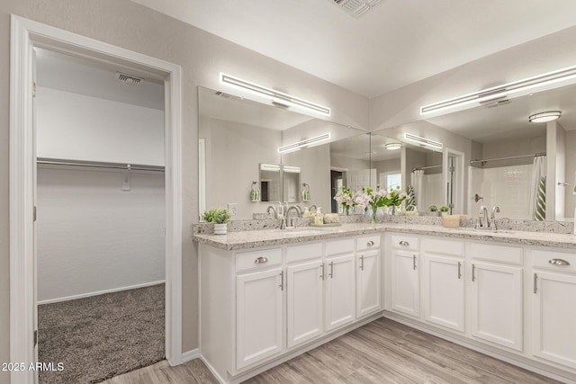 full bath featuring double vanity, a spacious closet, visible vents, and a shower with shower curtain