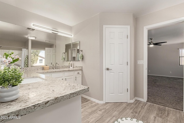 bathroom featuring double vanity, visible vents, a sink, and wood finished floors