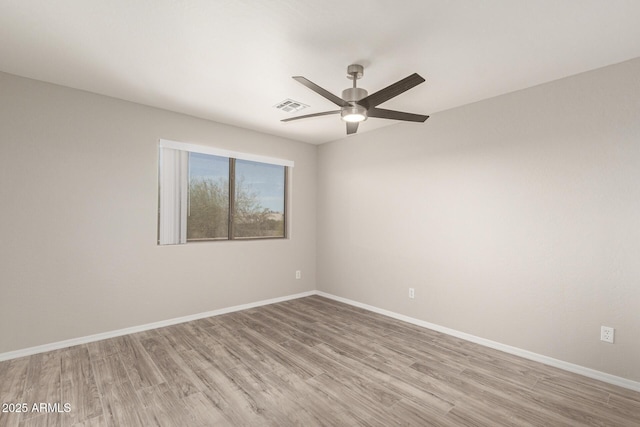 empty room featuring light wood finished floors, baseboards, visible vents, and a ceiling fan