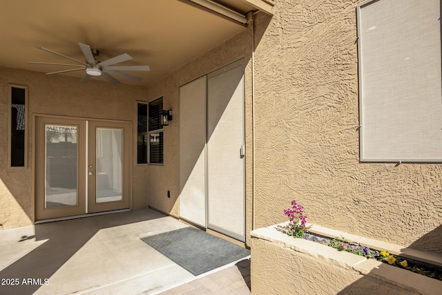 entrance to property with a patio area, french doors, a ceiling fan, and stucco siding