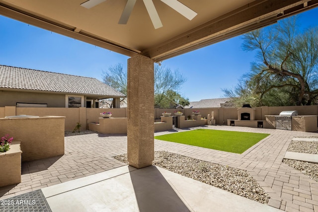 view of patio / terrace with exterior fireplace, a fenced backyard, exterior kitchen, and a ceiling fan