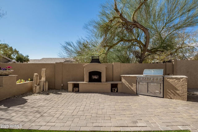 view of patio with fence, area for grilling, and an outdoor fireplace