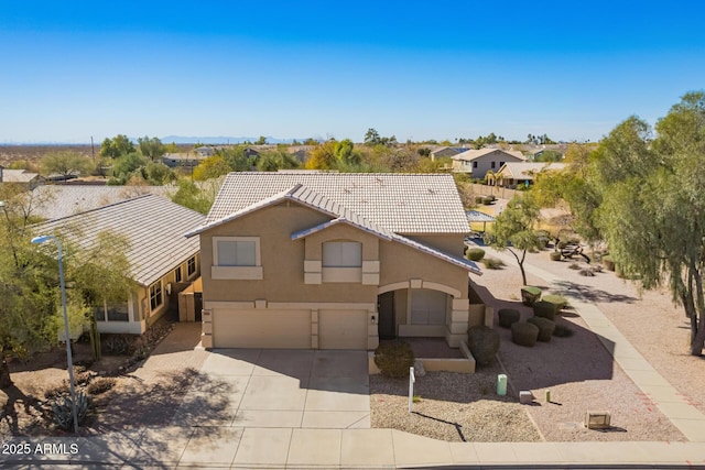 view of front of property with an attached garage, driveway, a tiled roof, and stucco siding