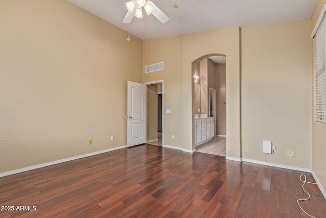 unfurnished bedroom with arched walkways, visible vents, baseboards, and wood finished floors