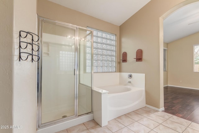 full bath featuring tile patterned flooring, baseboards, a bath, and a shower stall