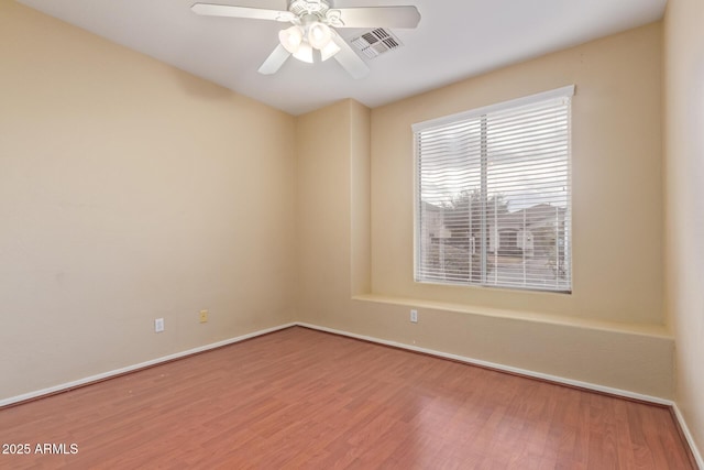 empty room with baseboards, wood finished floors, visible vents, and a ceiling fan