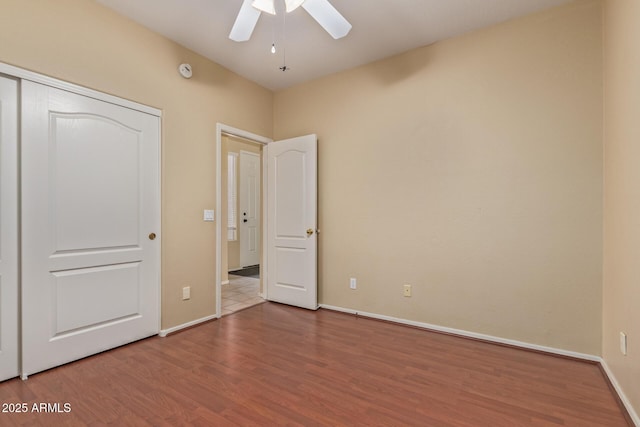 unfurnished bedroom featuring a ceiling fan, a closet, baseboards, and wood finished floors