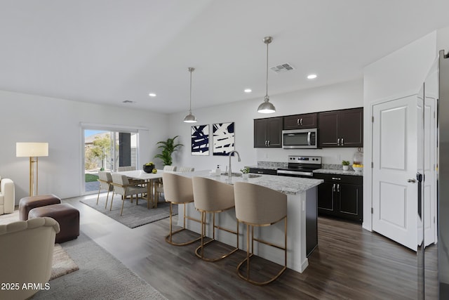 kitchen featuring dark brown cabinetry, sink, a kitchen breakfast bar, stainless steel appliances, and a kitchen island with sink