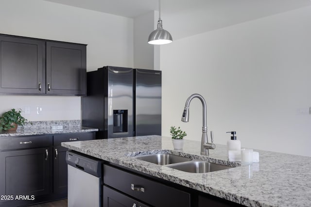 kitchen with pendant lighting, sink, stainless steel appliances, and light stone countertops