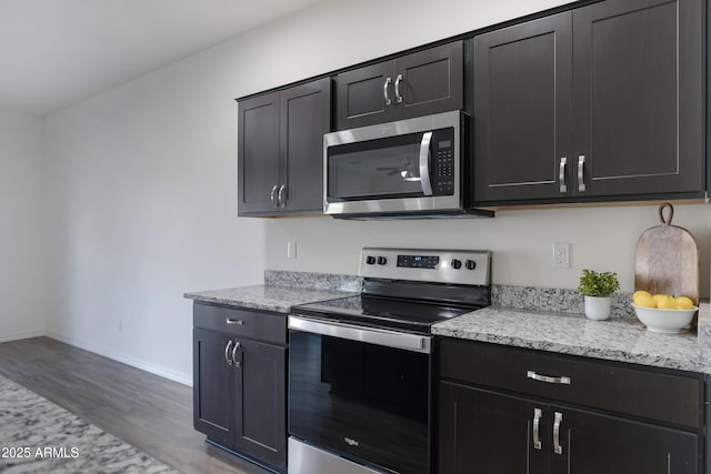 kitchen featuring hardwood / wood-style flooring, appliances with stainless steel finishes, and light stone countertops