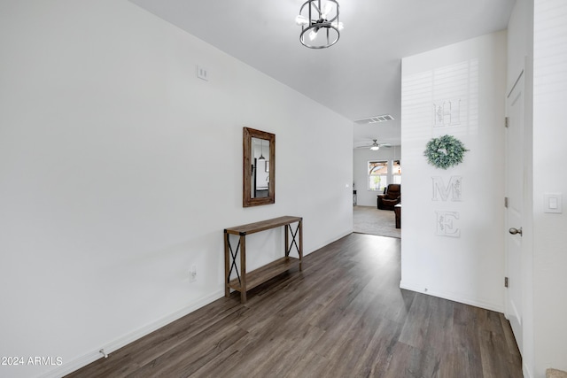 hall with dark wood-type flooring and an inviting chandelier