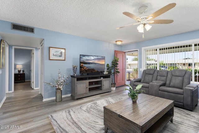 living room with visible vents, a ceiling fan, a textured ceiling, light wood-type flooring, and baseboards