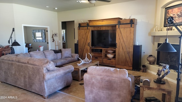 tiled living room featuring a barn door and ceiling fan